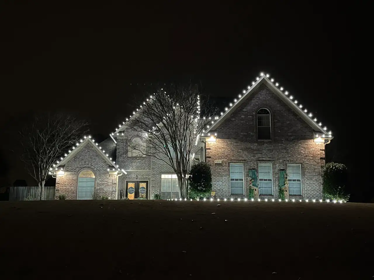Brick home with cool white C9 lights outlining every gable and a lit front-yard tree